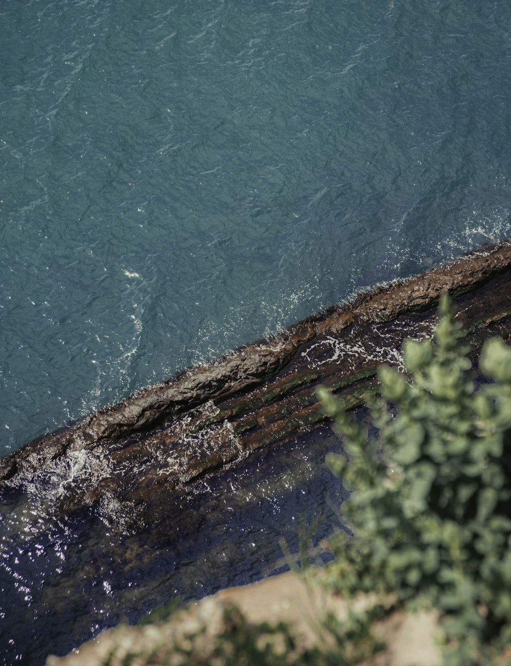 a man standing on the edge of a cliff next to a body of water