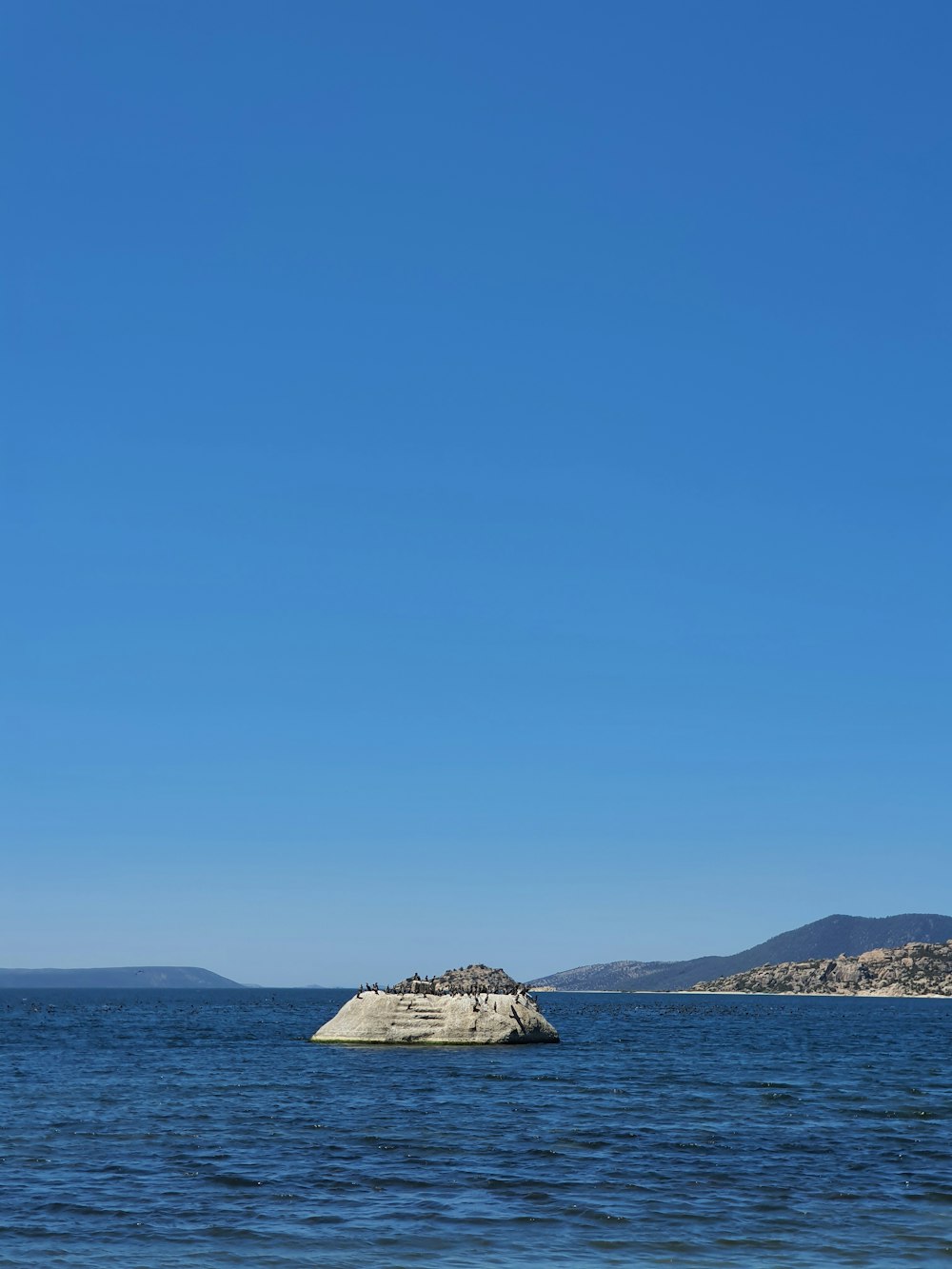 a sail boat is in the water near a rock