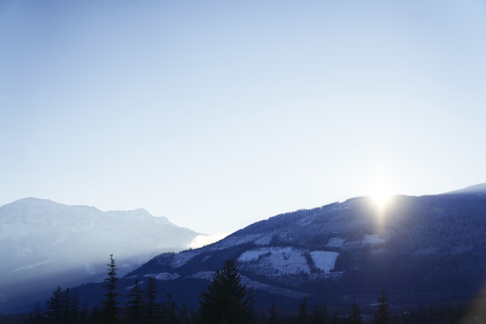 the sun shines brightly on a snowy mountain