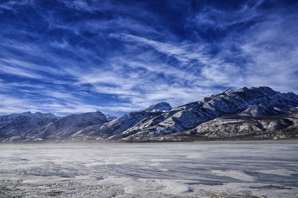 a mountain range covered in snow under a blue sky