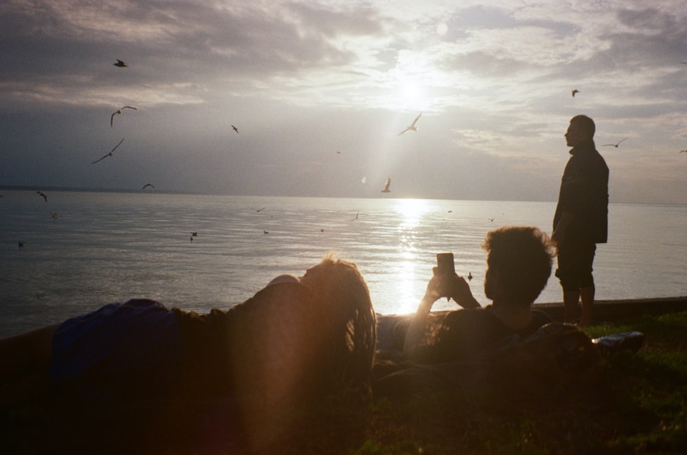 a couple of people sitting on top of a grass covered field