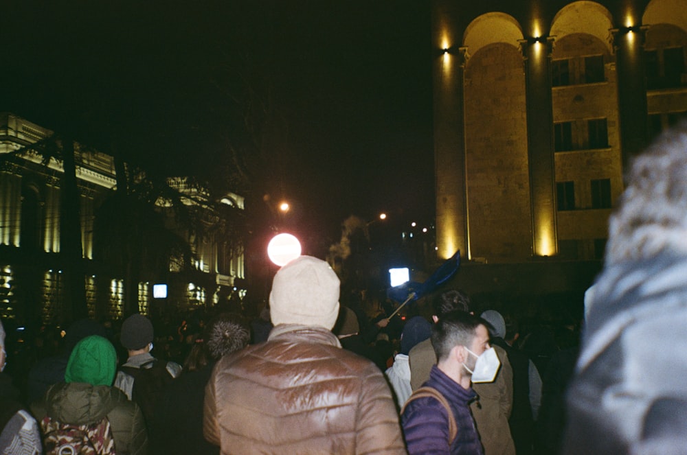 a crowd of people standing around a building at night