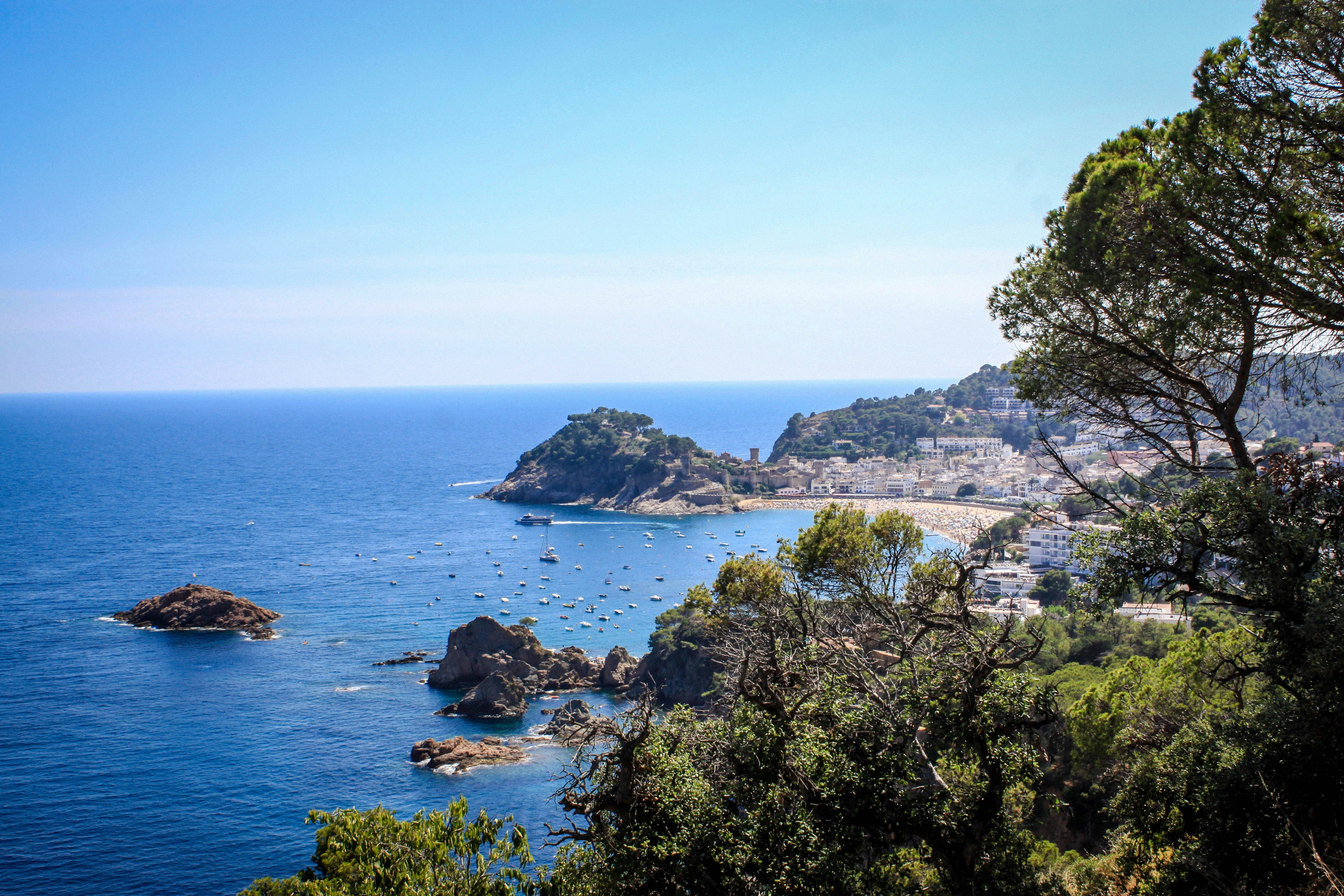 A scenic view of a beach with many boats in the water photo Free Tossa de mar Image on Unsplash