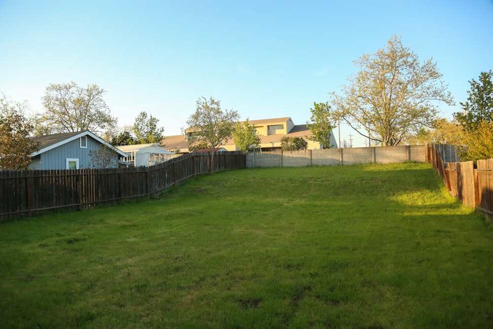 a grassy yard with a fence and a house in the background