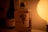 A bottle of Hibiki Suntory Whisky is prominently featured against a warm, dimly lit background. To the left, there is another bottle, partially visible, and on the right, a soft glowing light creates an intimate atmosphere.