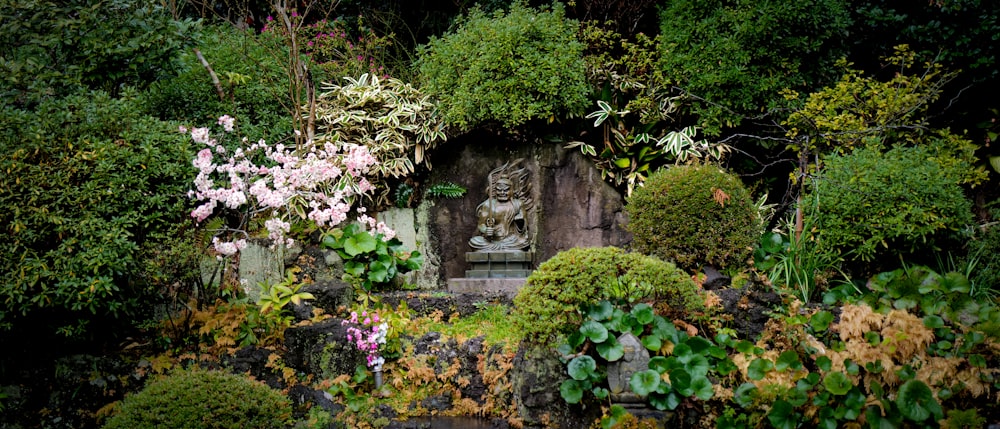 a garden with a buddha statue surrounded by trees