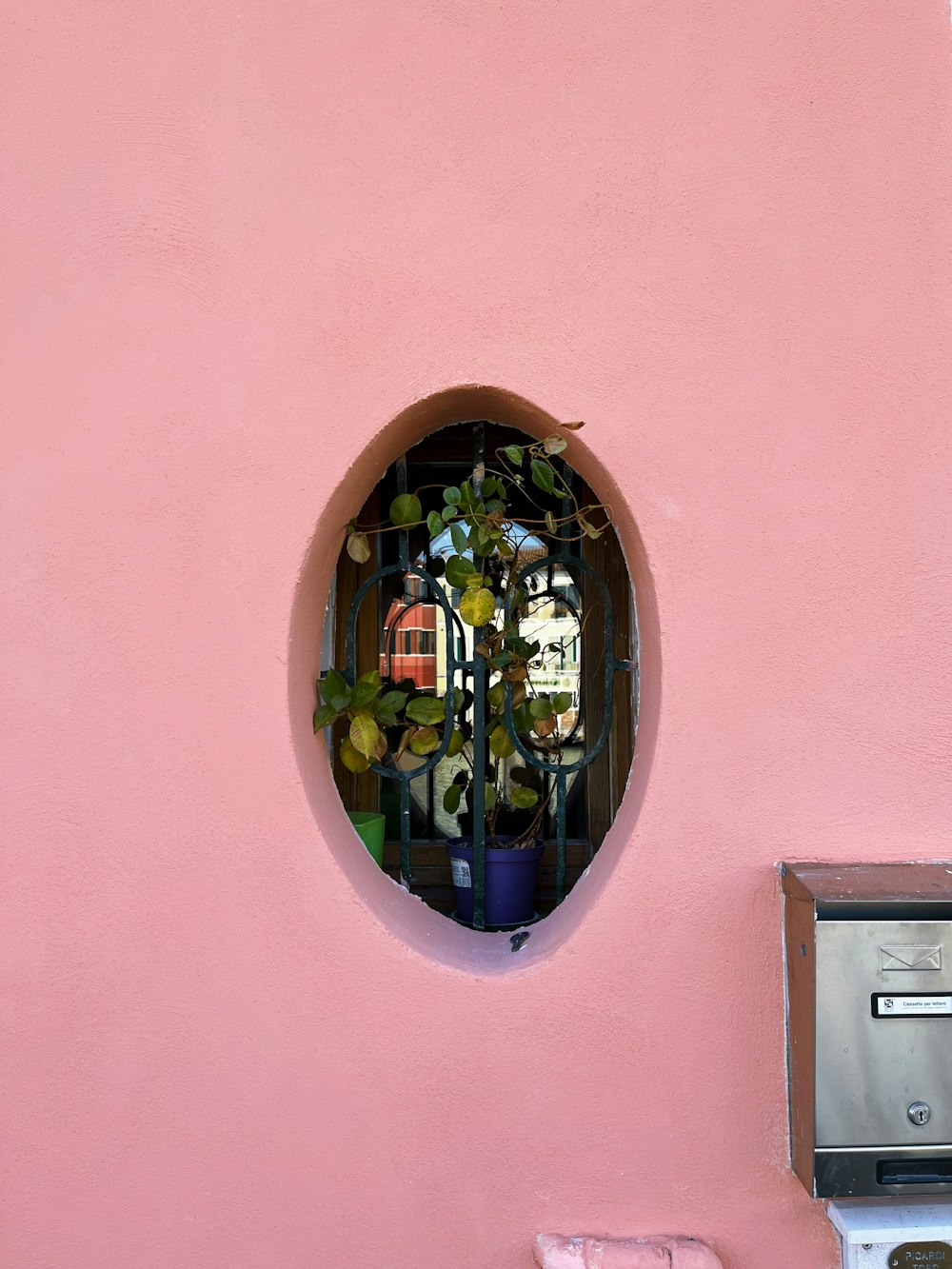 a pink wall with a round window and a mailbox