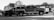 A black and white image featuring multiple emergency response vehicles, including a fire truck marked 'Waco Fire Battalion Chief' and another vehicle labeled 'Elm Mott'. The scene is outdoors with trees in the background and the vehicles are parked on a gravel surface.