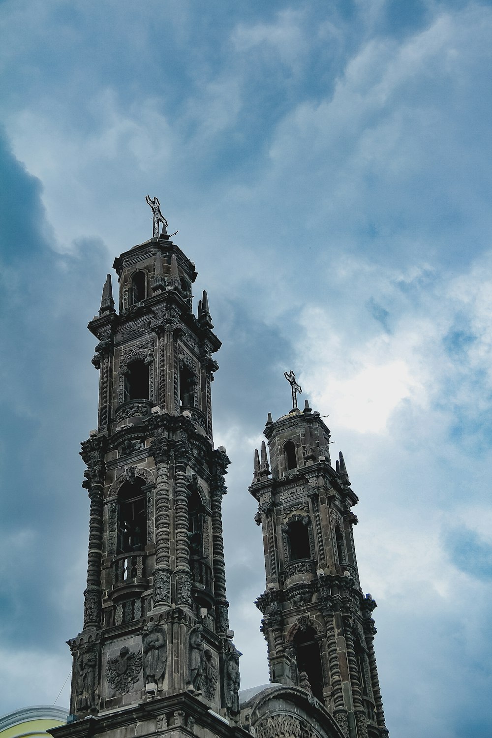 two tall towers with statues on them against a cloudy sky