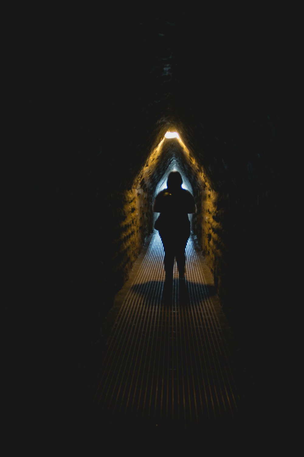 a person standing in a tunnel with a light at the end