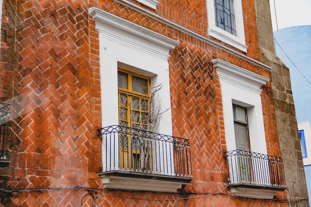 a red brick building with a yellow door and balcony