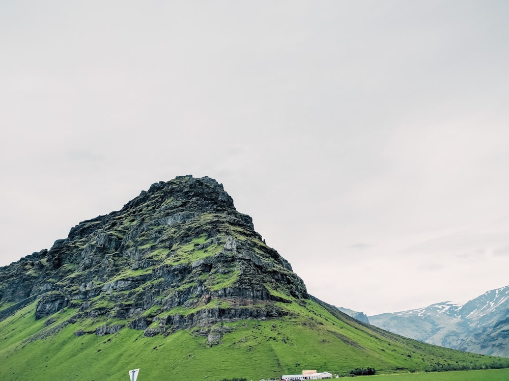 a green mountain with a sign in the foreground