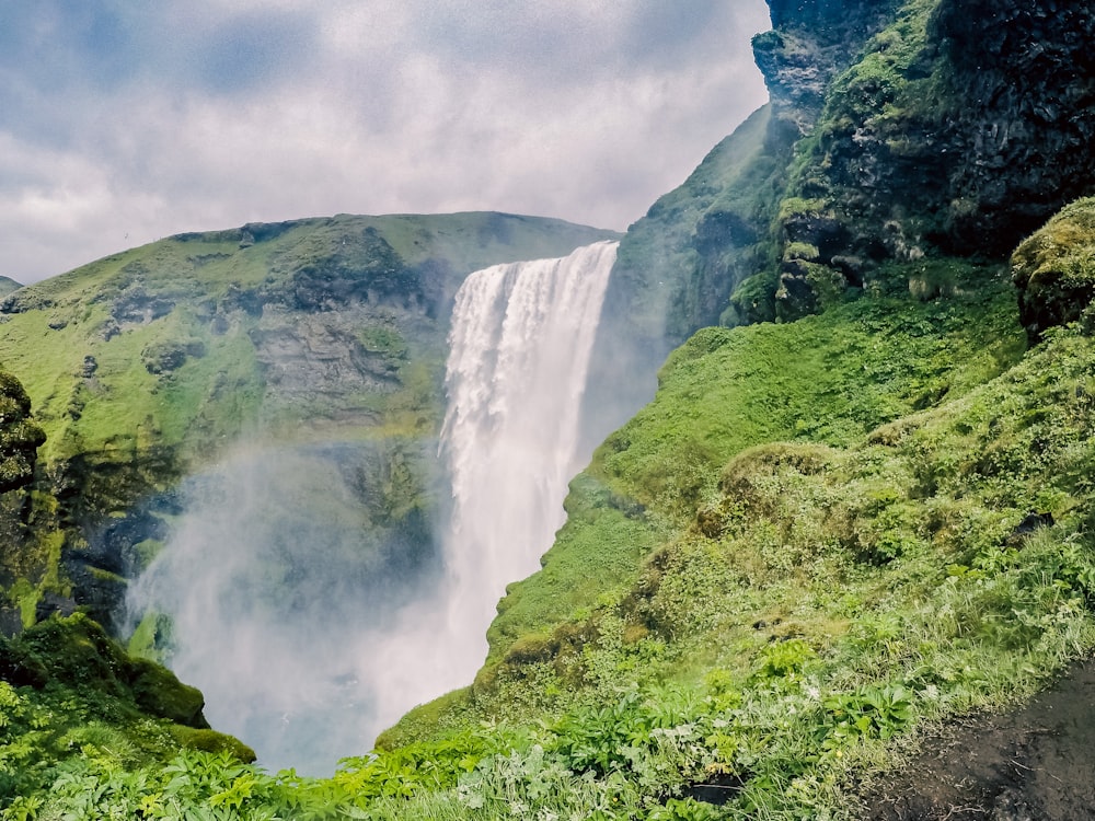 a large waterfall is in the middle of a green valley