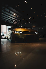 A sleek black car with yellow accents parked under bright showroom lights.