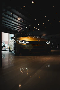 A sleek black car with yellow accents parked under bright showroom lights.