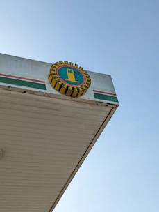 A bright gas station canopy with multiple fuel pumps and a clear blue sky.