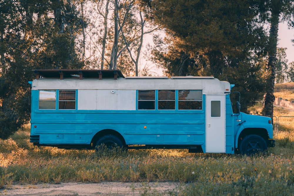 a blue and white bus parked in a field