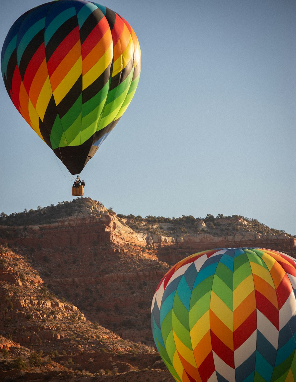 a couple of hot air balloons flying over a mountain