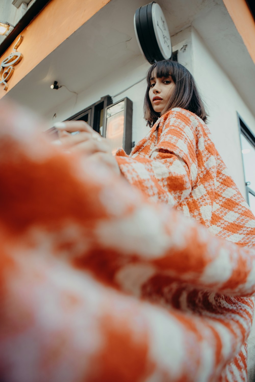 a woman in an orange and white checkered coat