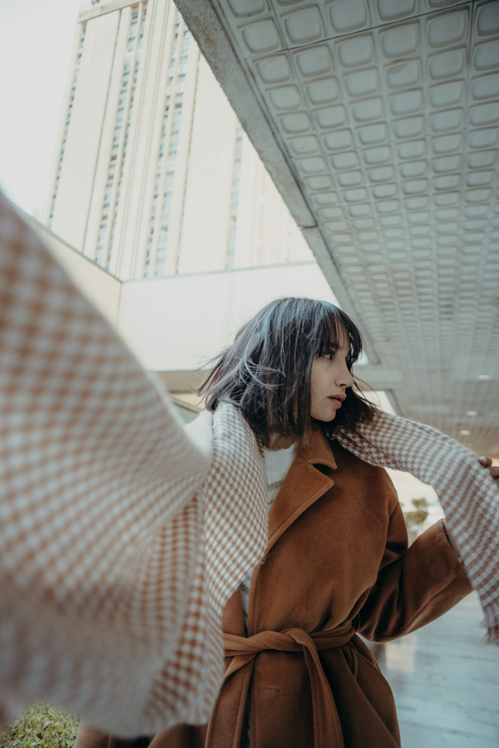 a woman in a brown coat and checkered scarf