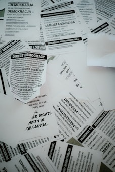 A collection of scattered flyers and papers with text related to concepts of democracy, rights, and anarchism. The papers are primarily in black and white and feature both English and Polish text.
