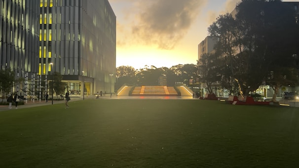 International students walking through a sleek, glass-covered campus building in Toronto at dusk.
