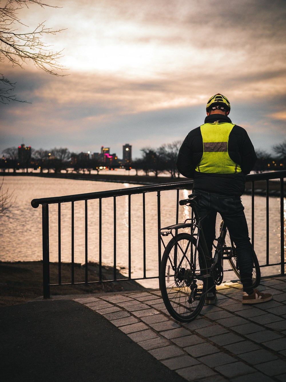 Un hombre parado junto a una bicicleta junto a un cuerpo de agua