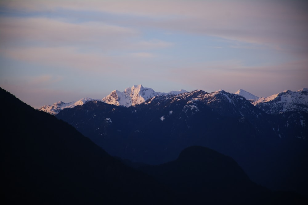 Una cadena montañosa con montañas cubiertas de nieve al fondo