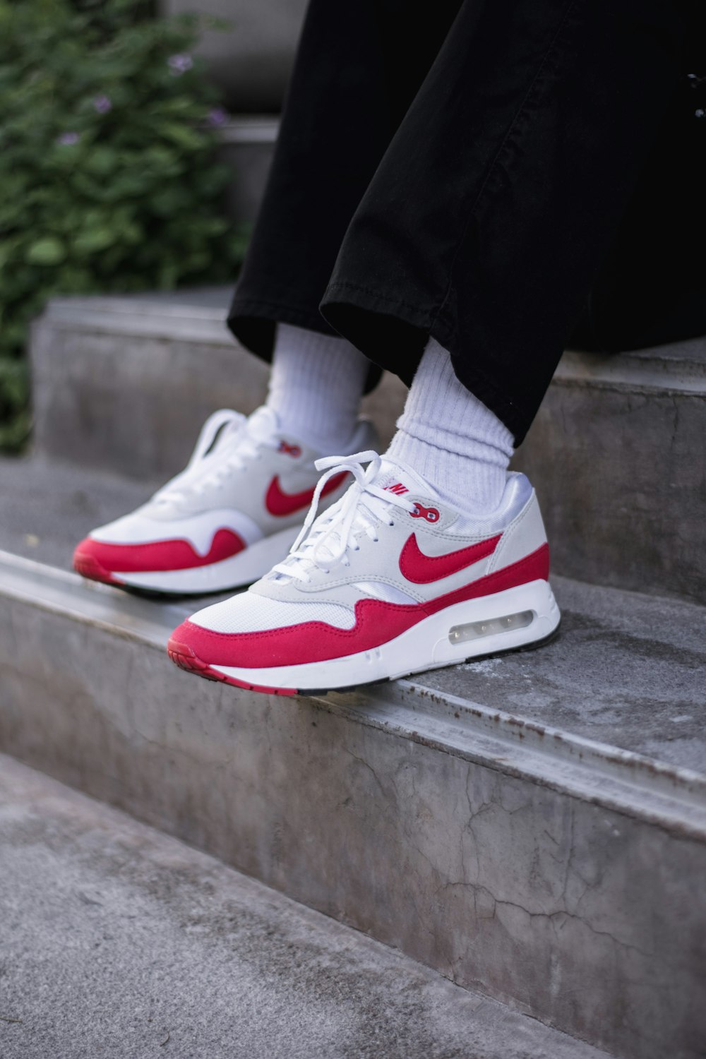 a person wearing white and red sneakers on some steps