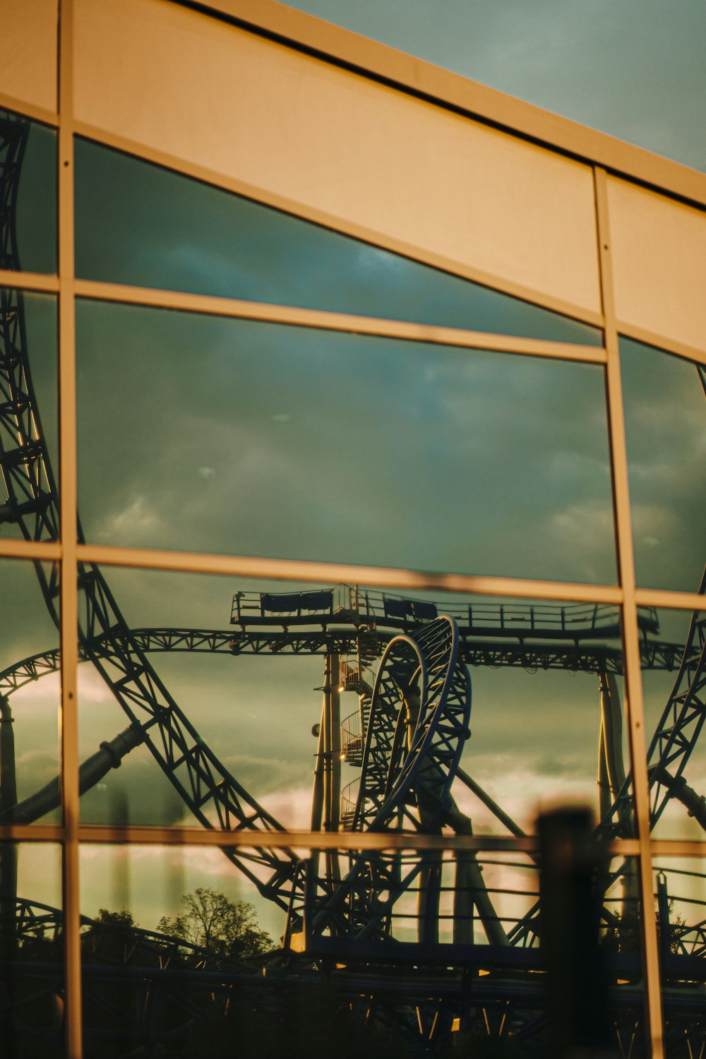 a reflection of a roller coaster in a window