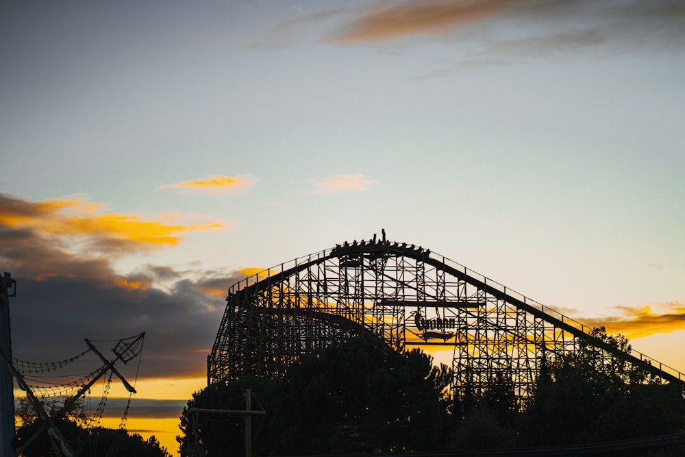 a roller coaster at sunset with the sky in the background