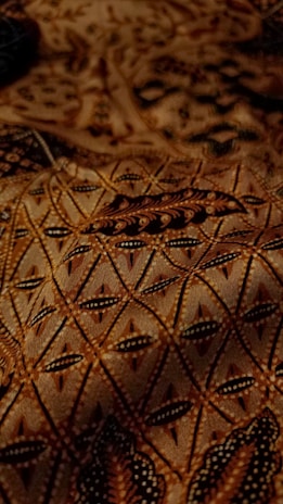 Elegant Arabian-inspired pattern in deep brown and gold hues, softly illuminated against a black backdrop.