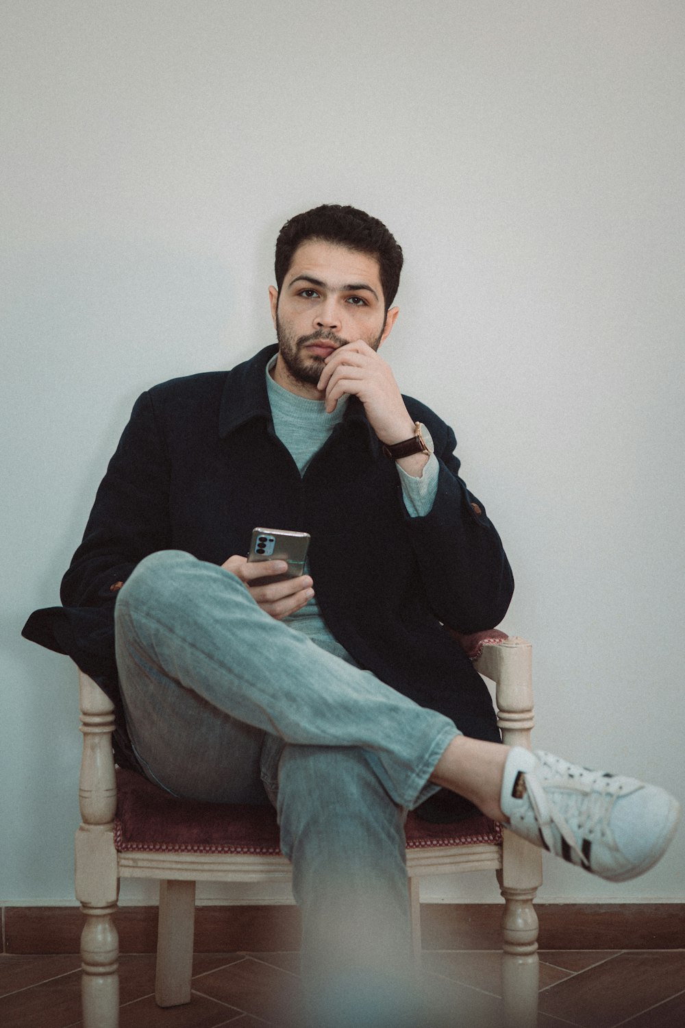 a man sitting on a chair holding a cell phone