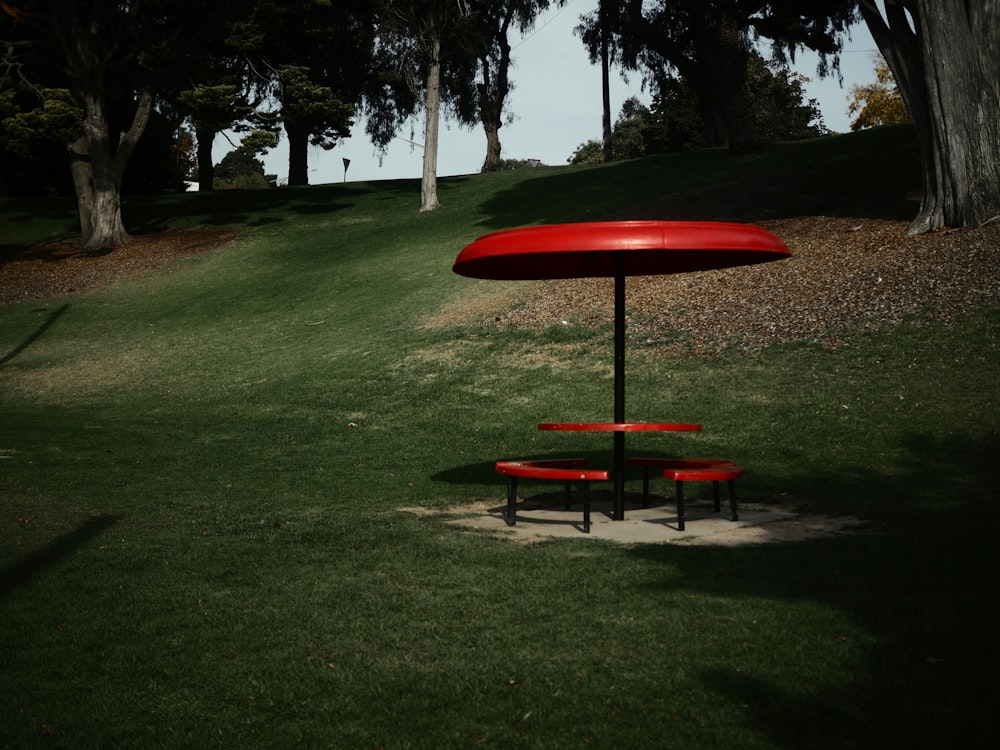 a red table and two red benches in the grass