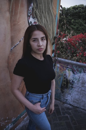 Young woman in a black oversized t-shirt and cargo pants standing against a minimalist urban wall.