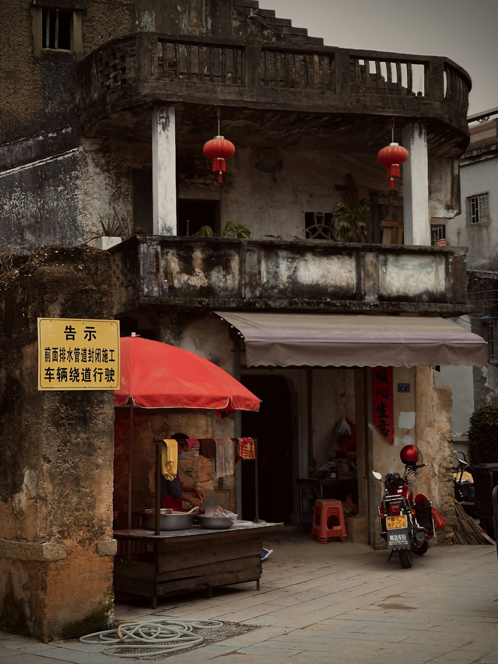 a motorcycle parked in front of a building with a red umbrella