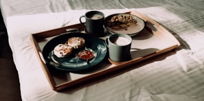 A morning scene with sunlight streaming through a window illuminating a breakfast tray with coffee and pastries