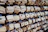 Wooden ema plaques hang densely on a structure, each displaying handwritten messages or prayers in various languages. Many of the plaques feature a printed design of a flower and cart, along with stamps or seals.