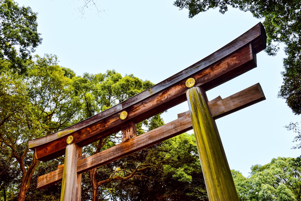 a wooden structure with two columns in front of trees