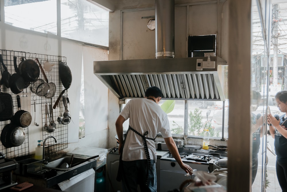 a man standing in a kitchen next to a window