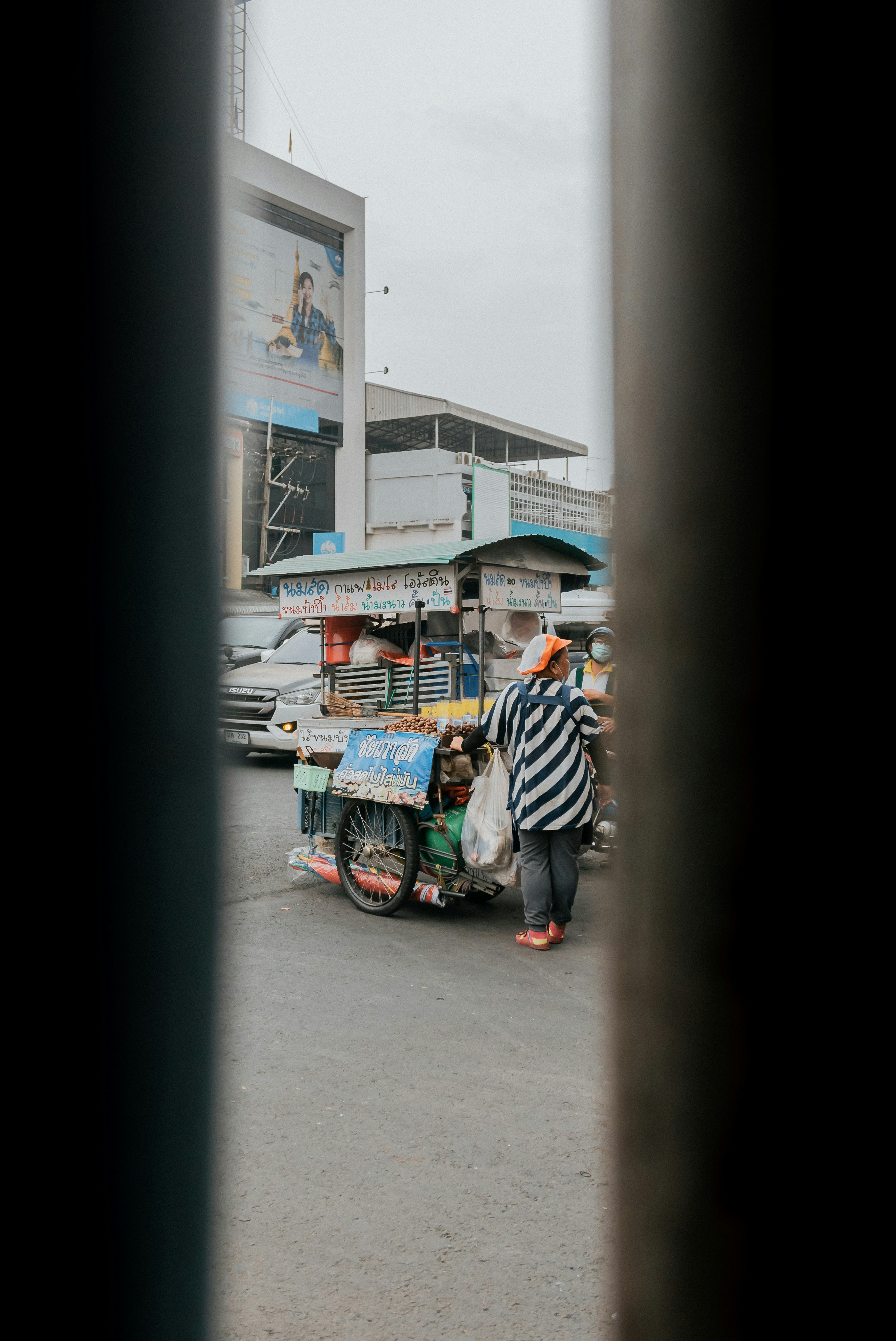 a man standing next to a food cart in a parking lot