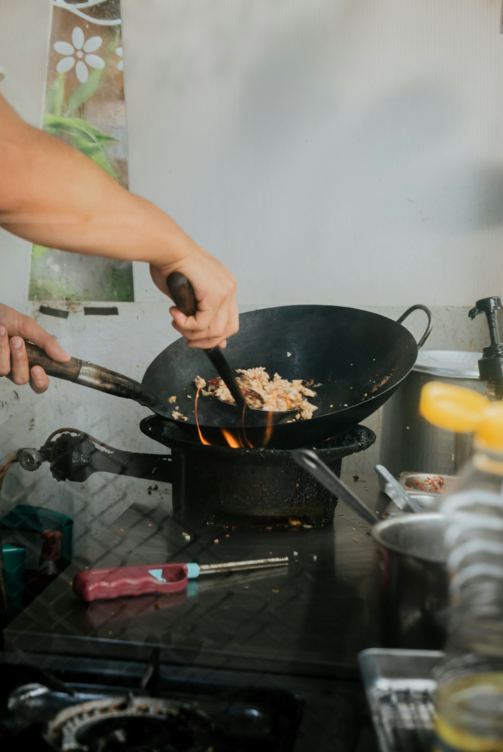 a person cooking food in a wok on a stove