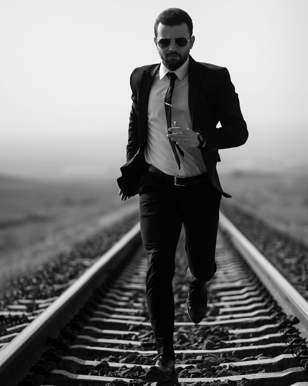 a man in a suit and tie running down a train track
