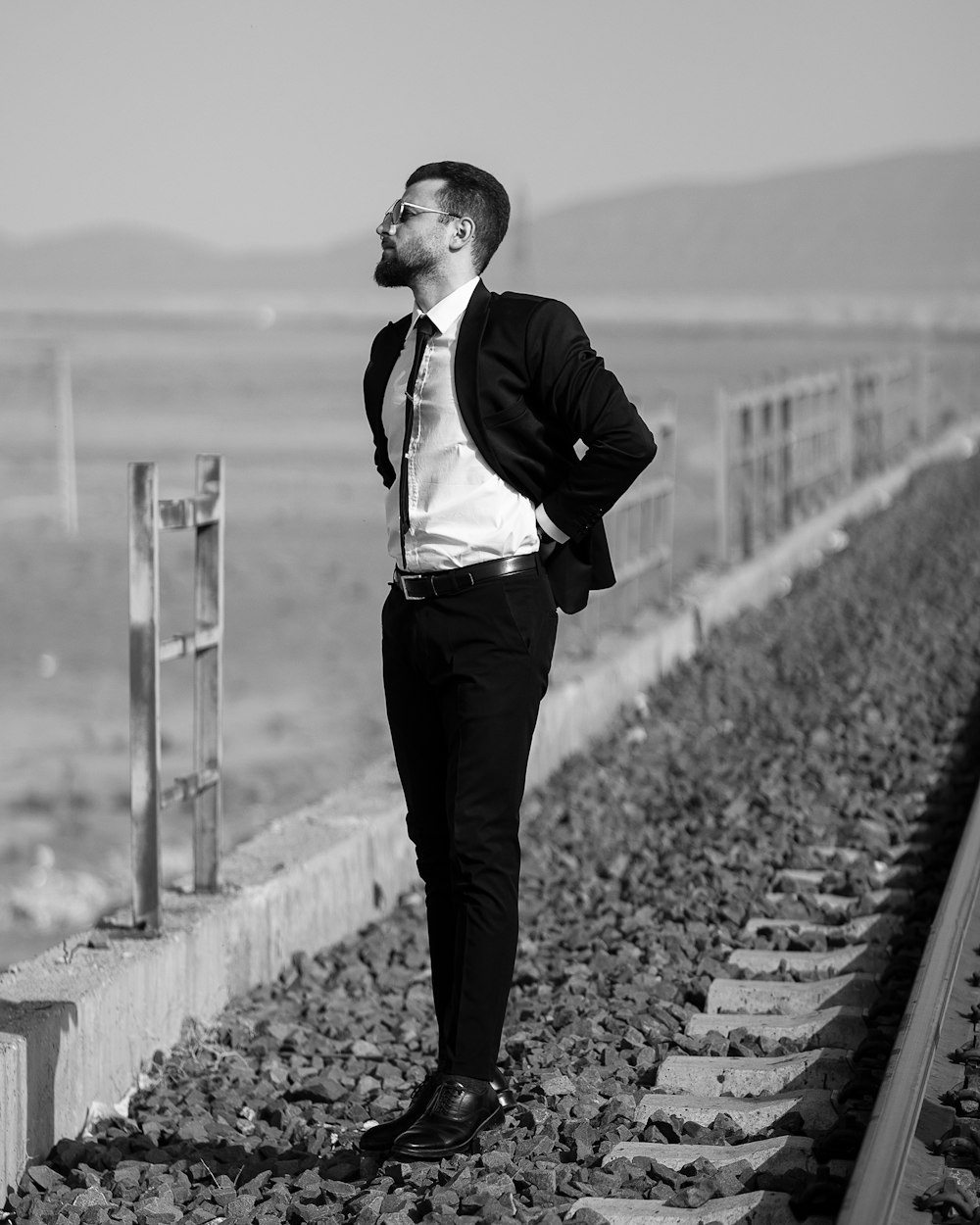 a man standing on a train track with his hands in his pockets