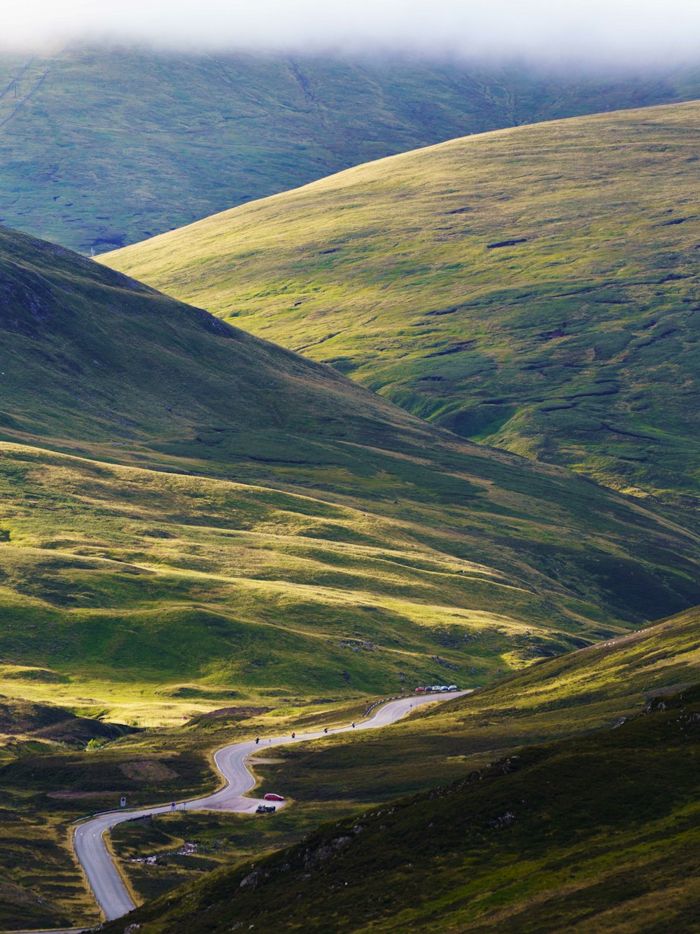 a winding road in the middle of a lush green valley