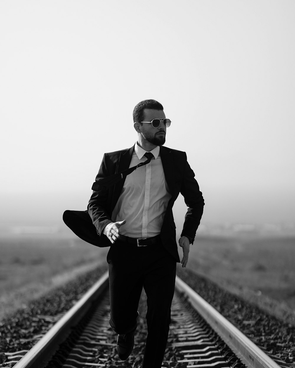 a man in a suit and tie standing on a train track