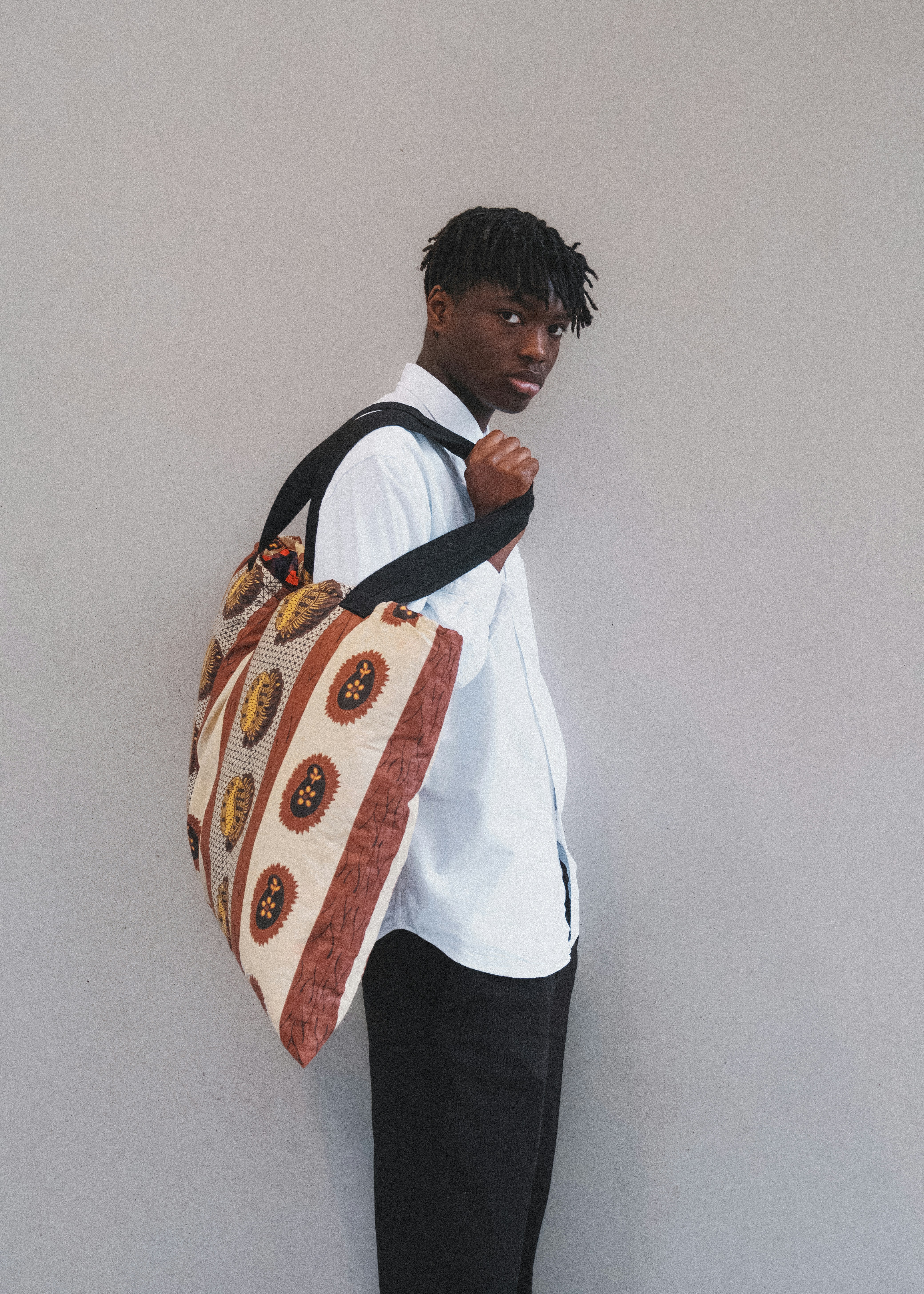 Un hombre con una bolsa de pie contra una pared