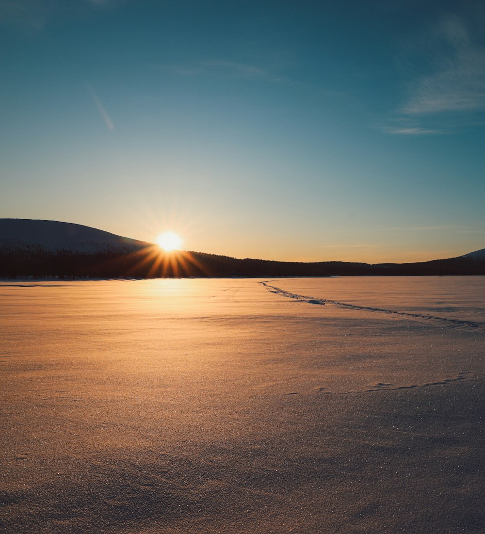 the sun is setting over a frozen lake