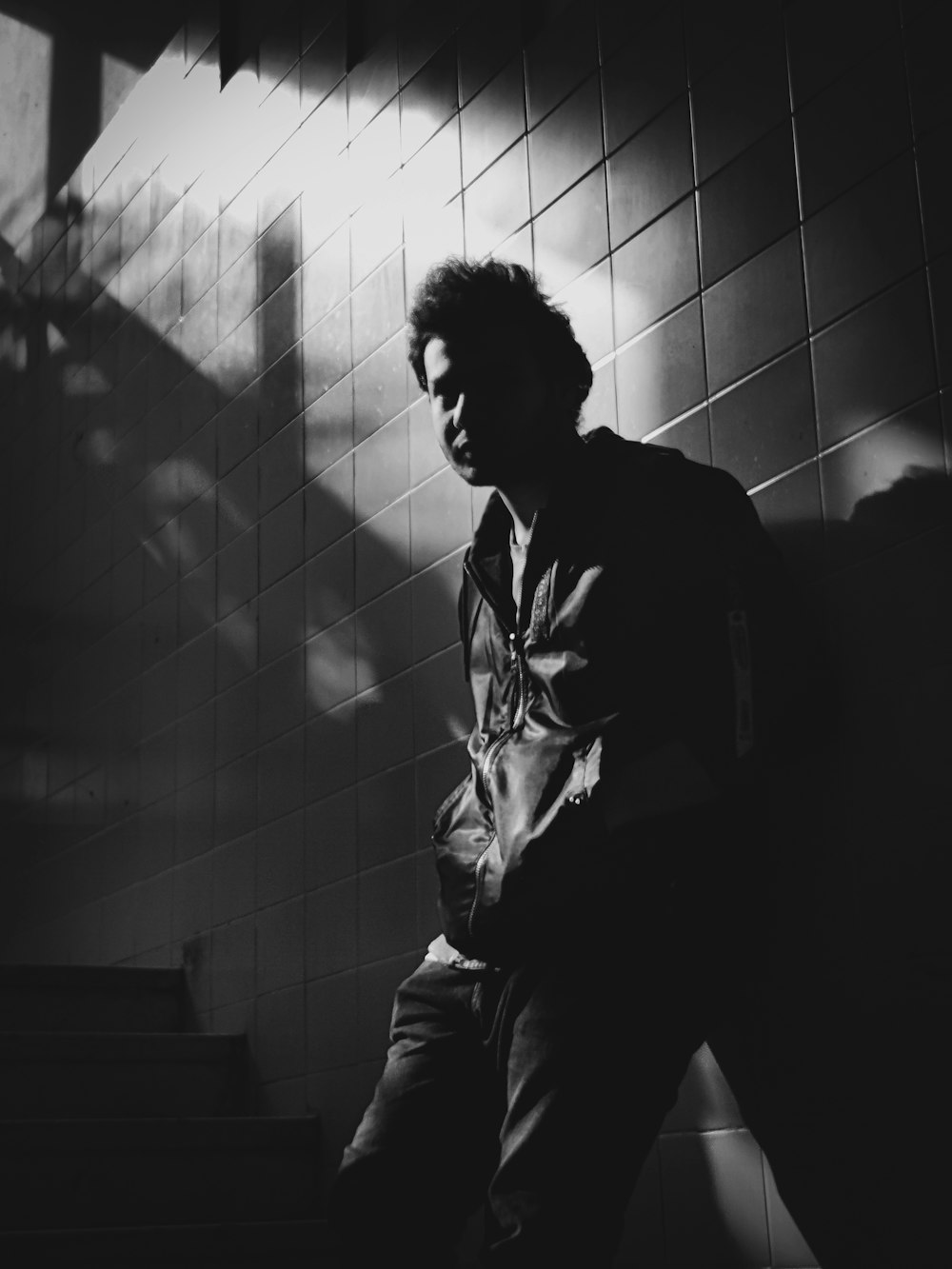 a black and white photo of a man leaning against a wall