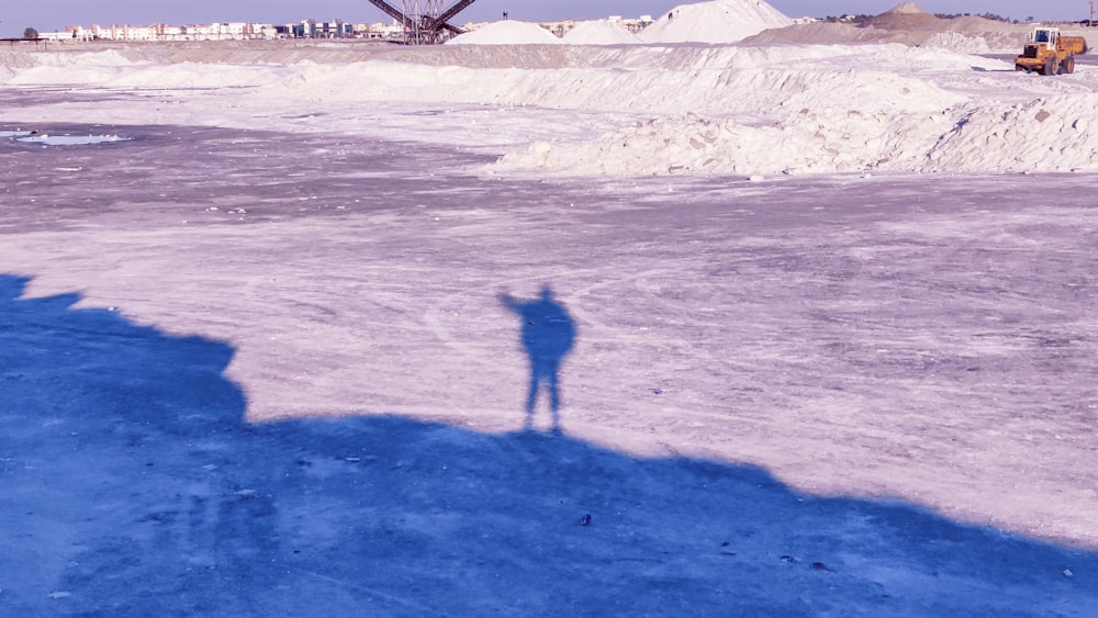 a shadow of a person standing in the snow